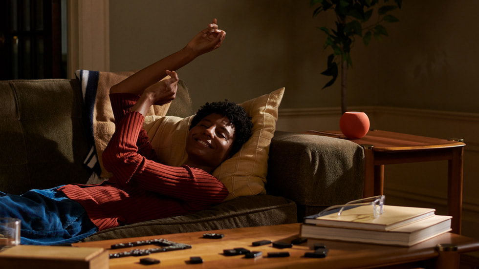 Een man ligt op de bank te luisteren naar muziek uit HomePod mini.