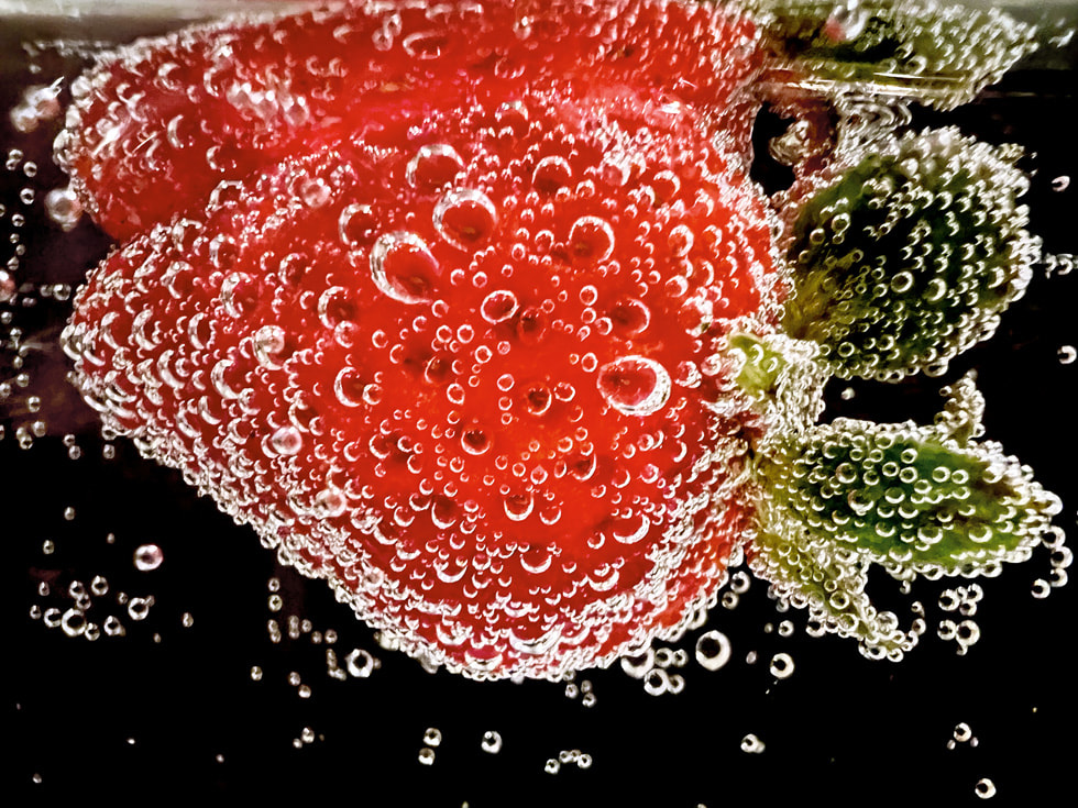 iPhone 13 Pro ile çekilen, Ashley Lee imzalı kazanan makro fotoğraf, maden suyu baloncuklarıyla çevrelenmiş bir çileğin yakın çekim görüntüsünü gösteriyor.
