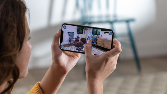 Elinde AR deneyiminin gösterildiği bir iPhone Xs tutan kadın.