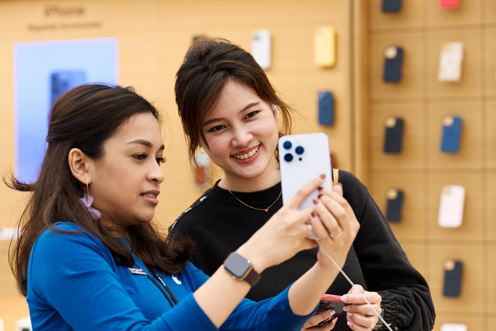 En Apple Orchard Road-medarbetare visar upp iPhone 14 Pro i silver för en kvinna.