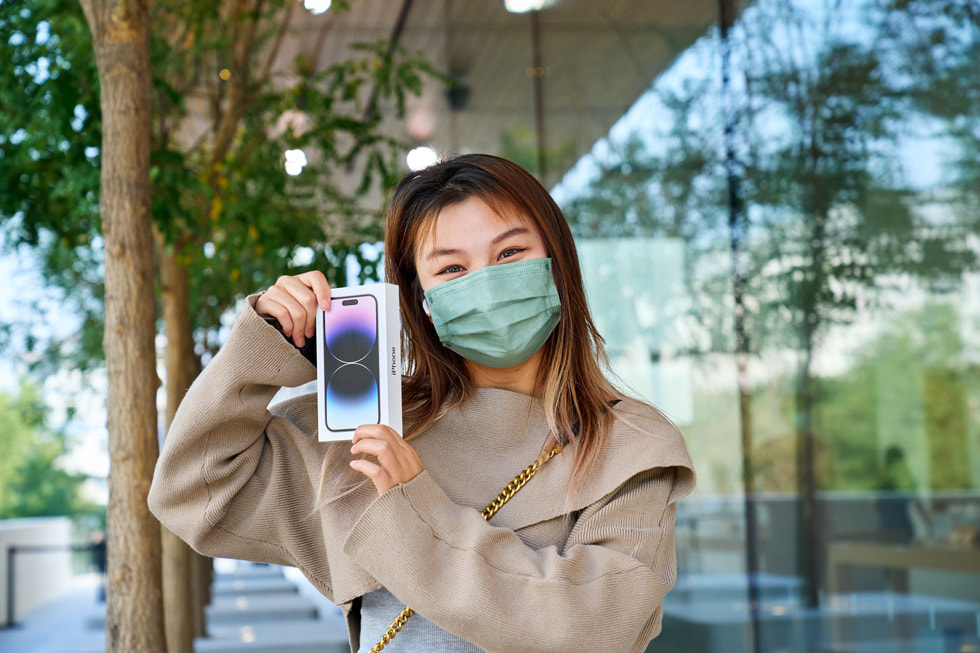 En kvinna håller i sin nya iPhone 14 Pro utanför Apple Sanlitun.