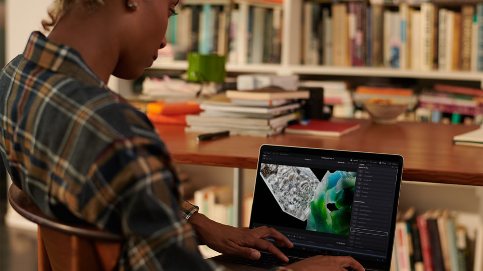 Kütüphane ortamında MacBook Pro kullanan bir kişi.