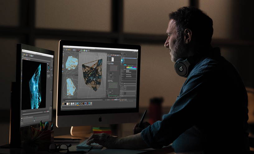 Bir iMac ve ek bir monitörde 3D grafikleri gözden geçiren bir profesyonel.