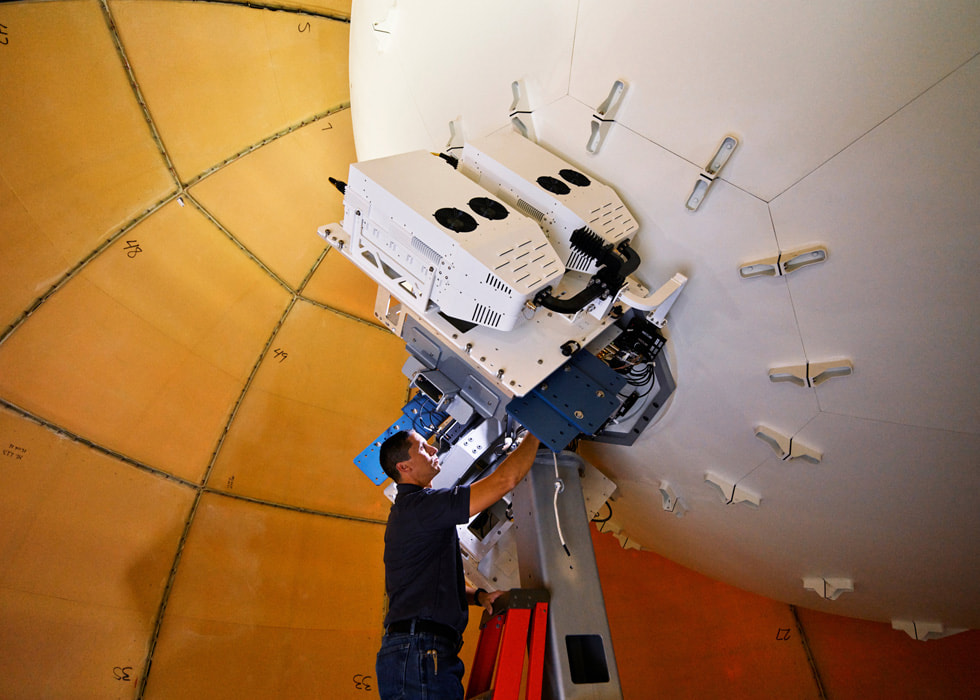 Un technicien en communications satellitaires, debout sur une échelle.