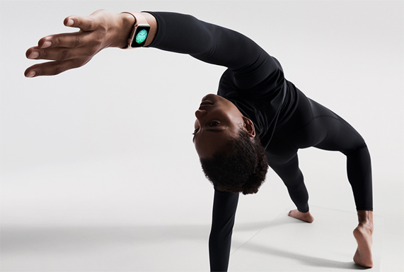 Altın renkli iPhone Watch Series 4 giymiş bir kadın mat üzerinde bir yoga duruşunda.