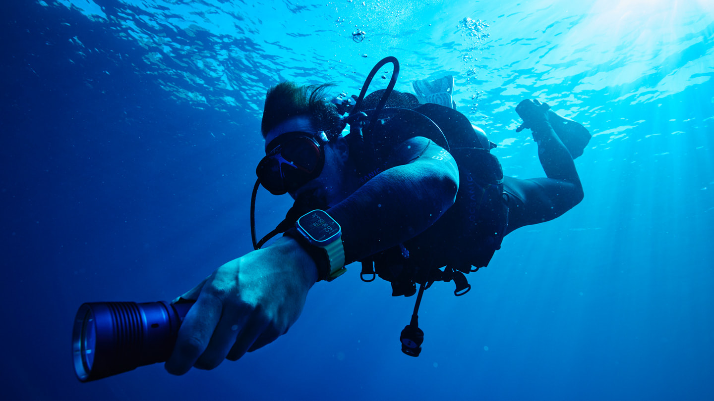 Oceanic+を搭載したApple Watch Ultraを着けて海面下を泳ぐスキューバダイバー。