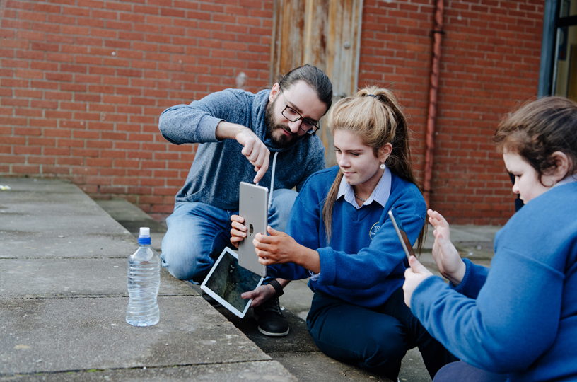 Una joven usa iPad para tomar una foto con la ayuda de un voluntario de Apple.