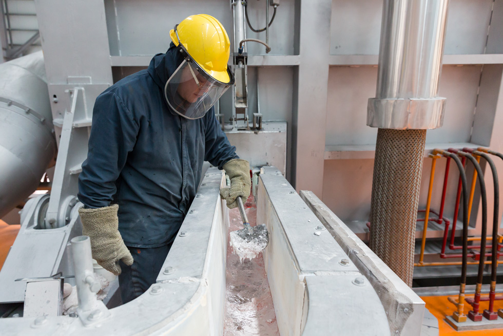 Een fabrieksmedewerker overziet het smeltproces in een aluminiumfabriek.