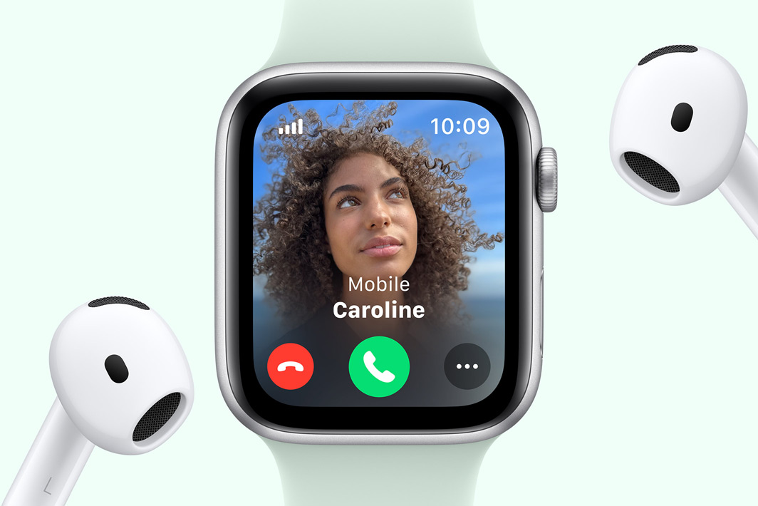 Apple Watch SE showing an incoming call, next to a pair of AirPods