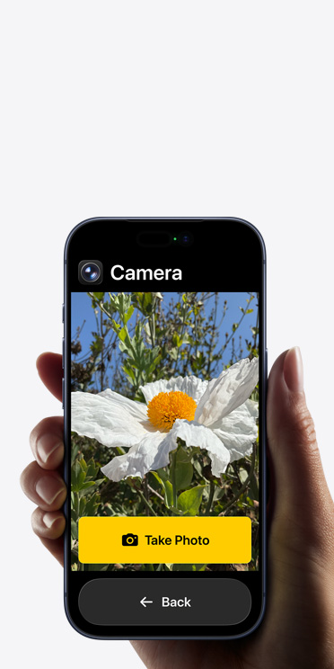 iPhone 17 Pro screen showing simplified Camera app interface with a white flower in the frame, “Take Photo” button and “Back” button below