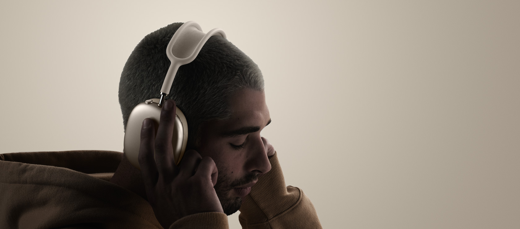 Person mit AirPods Max 2 Kopfhörern, Seitenansicht, berührt Ohrmuschel