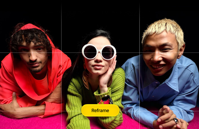 Brightly hued closeup photo of three people leaning forward over a pink surface, a grid appears over it, along with a button that reads: Reframe