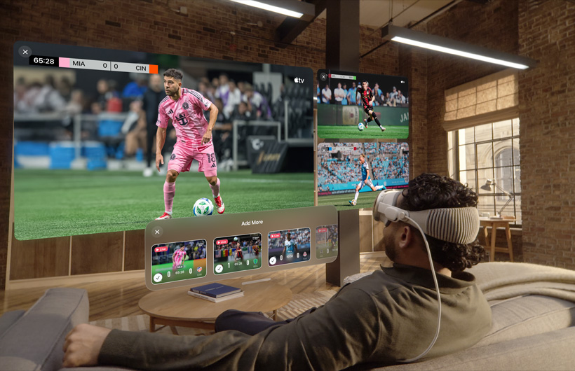一個人戴著 Apple Vision Pro 坐在客廳的梳化上。一個巨大的影片畫面及兩個較小的畫面在他面前顯現，各個畫面播放著不同體育賽事。大畫面下方有個選項視窗，顯示著「加入更多」