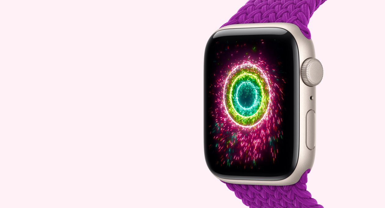 Apple Watch SE 3, aluminum case, starlight color, screen shows Activity Rings in the style of fireworks, right side exterior, Digital Crown dial, microphone, side button, Braided Solo Loop band, magenta color