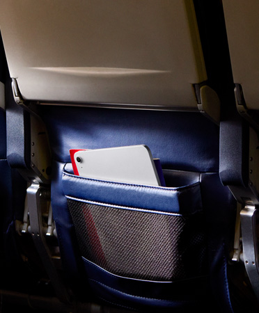 Ein vergessenes iPad Air in Silber in der Rückenlehnentasche eines Flugzeugsitzes