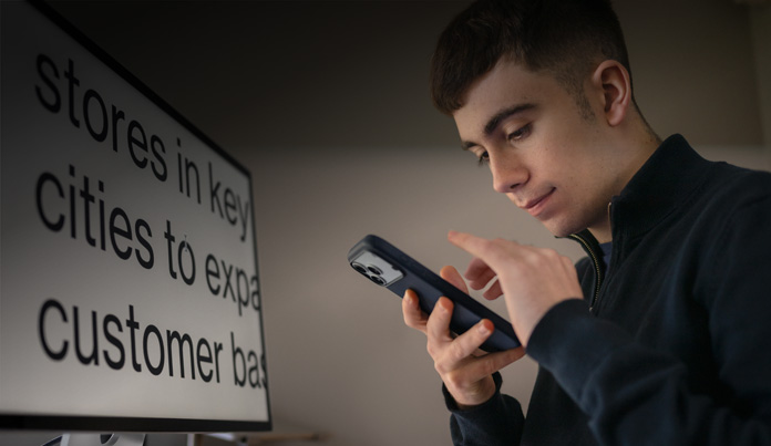 Ein Student schaut auf sein iPhone, während er es nah vor seinem Gesicht bedient