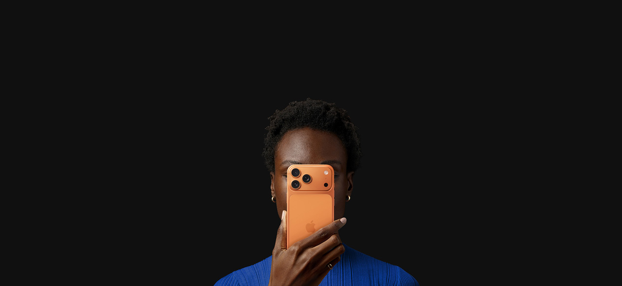 Iemand houdt een iPhone 17 Pro voor het gezicht, de achterkant is te zien, in de kleur Kosmisch Oranje.