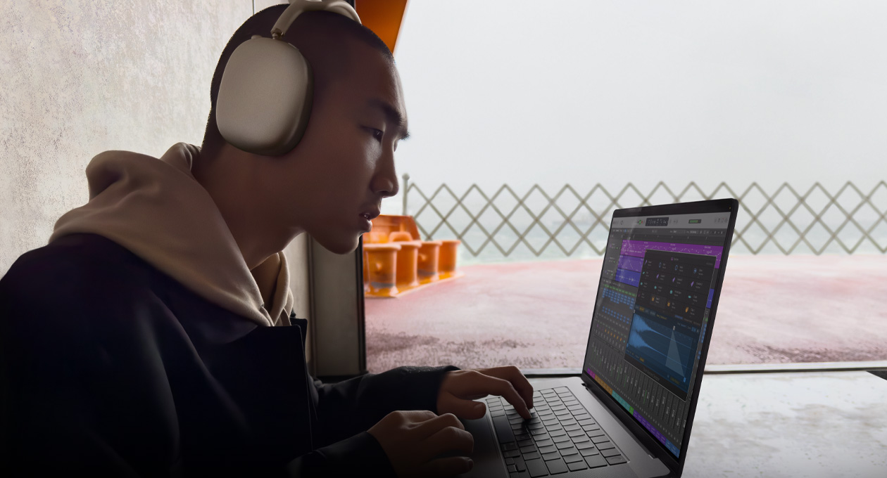 Vista lateral de una persona con unos AirPods Max que usa Logic Pro en una MacBook Pro de 16 pulgadas