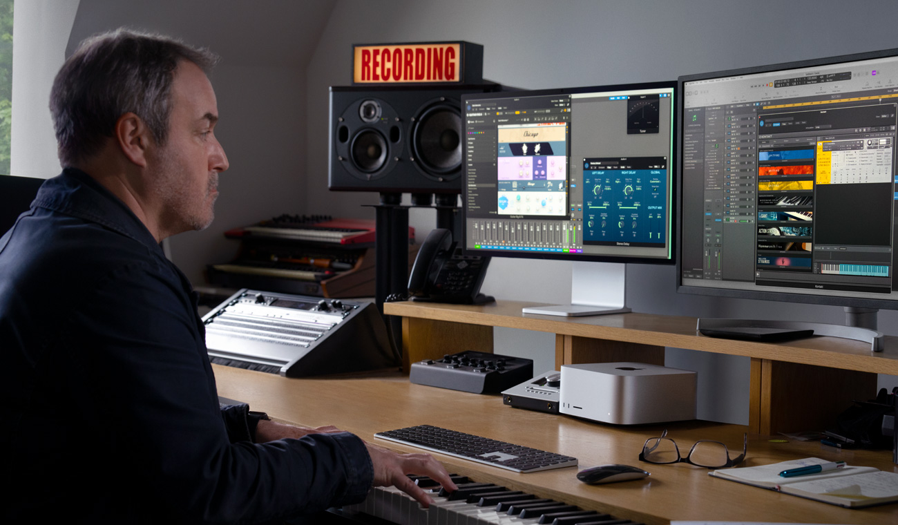1人のミュージシャンがピアノを使って、Mac StudioとStudio Displayでオーディオミックスを作成している