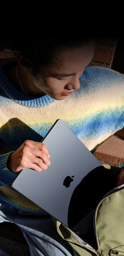 Une personne glissant un MacBook Air 15 pouces minuit dans un sac à dos.