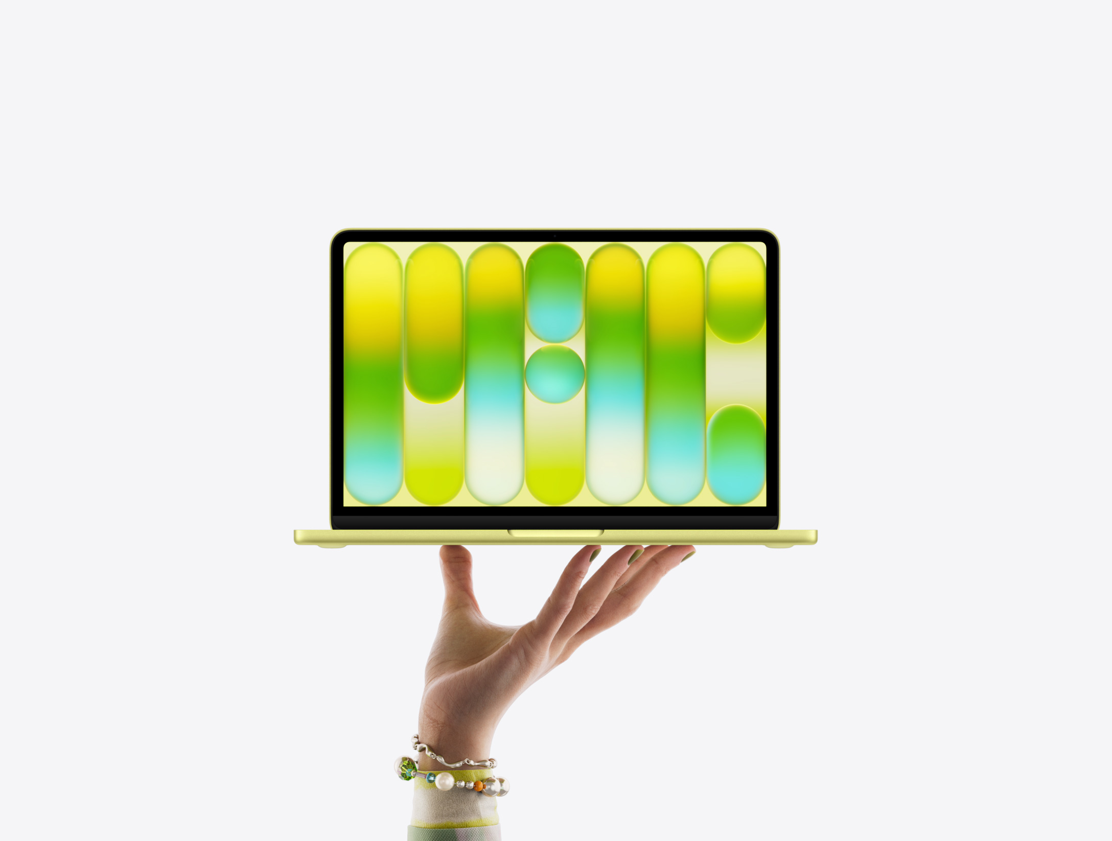 Un MacBook Neo de couleur agrume, tenu en équilibre sur le bout des doigts d’une main ouverte, écran affichant un motif abstrait coloré