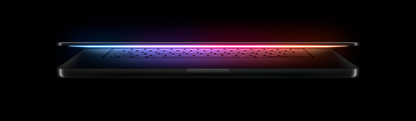 Het scherm van een deels geopende MacBook Pro werpt een veelkleurige gloed op het toetsenbord