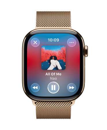 Kultatitaaninen Apple Watch ja milanolaisranneke, kellotaulussa näkyy Apple Music käytössä, läpikuultavat Liquid Glass ‑säätimet