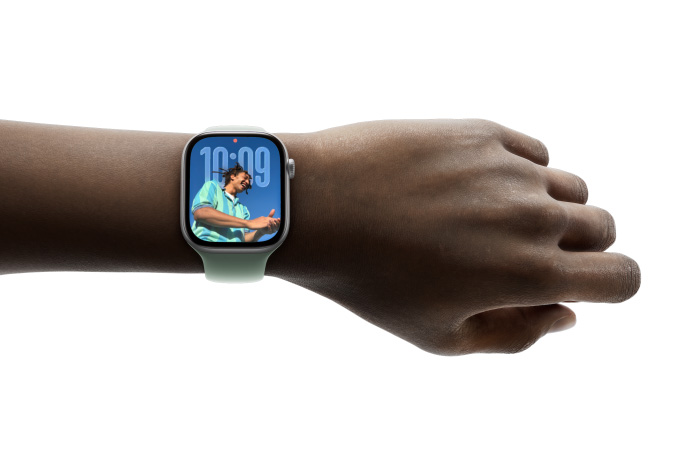Henkilön ranteessa on hopeanvärinen Apple Watch ja silikonikumiranneke, kellotaulussa näkyy Muistiinpanot-appi ja viesti