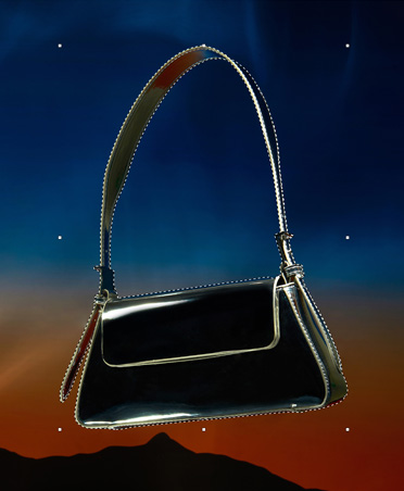 Un bolso negro delineado con líneas discontinuas, herramienta de selección, edición de imágenes, fondo de atardecer con silueta de montañas